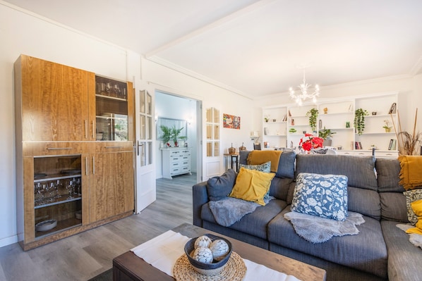 A modern living room with a sofa, a wooden cabinet, and a kitchen area in the background.