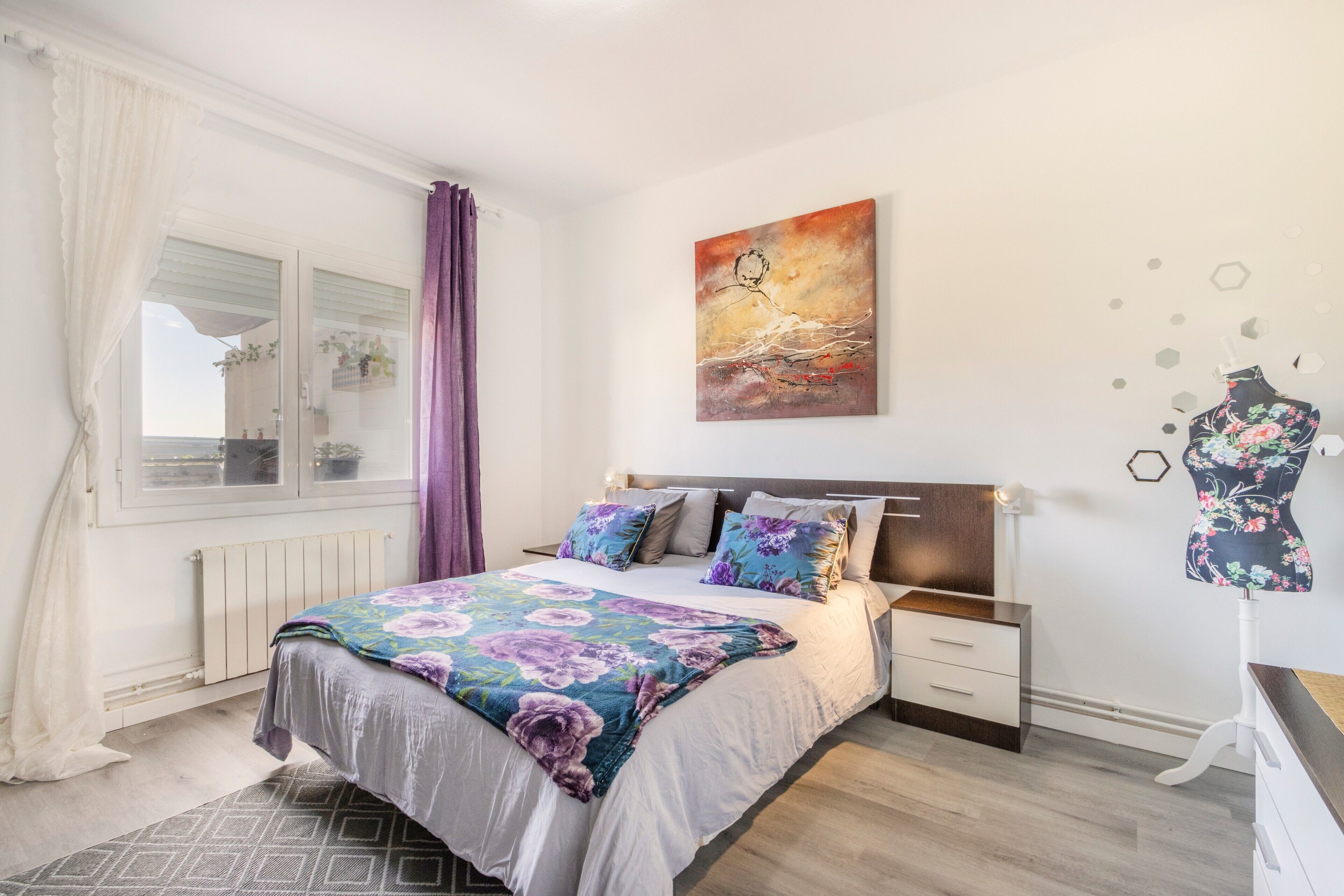 Un dormitorio con una cama, un aparador, un maniquí y un cuadro en la pared.
