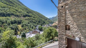 A stone building with a sign reading 'Casa Guillen' and a view of a valley with houses and greenery.