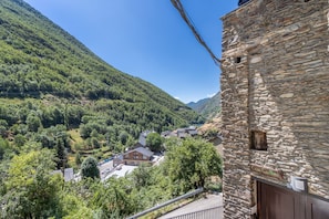 Um edifício de pedra com uma placa indicando 'Casa Guillen' e vista para um vale com casas e vegetação.