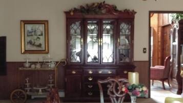 A traditional dining room with a wooden cabinet, a vintage chair, and a vase with flowers.