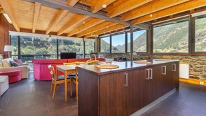 Una cucina moderna con isola centrale, travi in legno a soffitto e ampie finestre con vista sulle montagne.