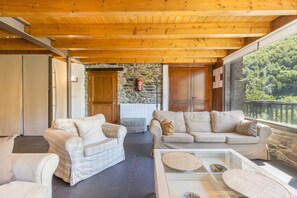 A cozy living area with two sofas, a glass coffee table, and a stone wall in the background.