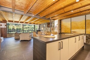 A modern kitchen with a large island, stone walls, and a view of greenery. - Country House 'Casa Guillem 3' with Lake View, Wi-Fi and Air Conditioning (Tavascan)