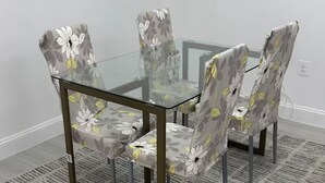 Un coin repas avec une table à plateau en verre et des chaises à motifs floraux.
