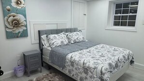 Une chambre à coucher avec un lit, des tables de chevet, un tapis, un tableau et une fenêtre.