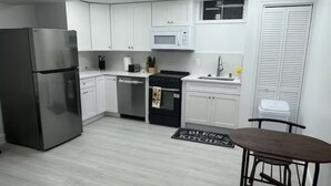 Une cuisine moderne avec des meubles blancs, un réfrigérateur en acier inoxydable, un four à micro-ondes et une cuisinière.