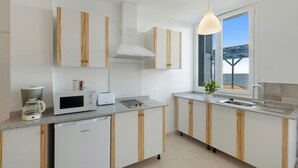Una cocina moderna con armarios blancos, microondas, cafetera y ventana con vistas.