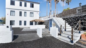 Un bâtiment blanc avec de nombreuses fenêtres, un mur en pierre et des palmiers.