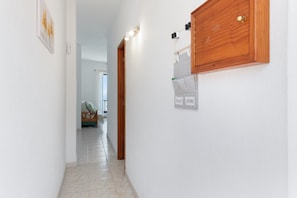 A hallway with a wooden cabinet, a light switch, and a sign on the wall.