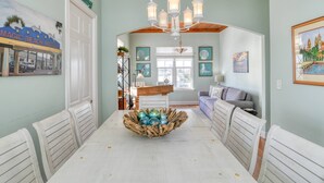 A dining area with a white table, chairs, and a centerpiece of glass bowls. - The Beach Escape (St. Augustine)