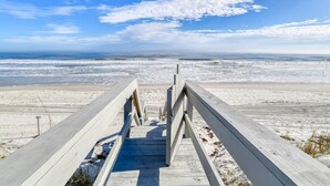 A wooden boardwalk leading to a beach with a clear sky. - The Beach Escape (St. Augustine)