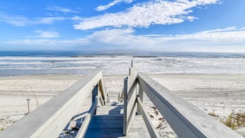 A wooden boardwalk leading to a beach with a clear sky.