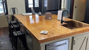 A kitchen with a wooden island, stainless steel appliances, and a black chair.