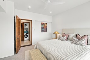 Ein Schlafzimmer mit einem großen Bett, einer Waschmaschine in der Ecke, einem Gemälde an der Wand und einem Nachttisch mit Lampe.