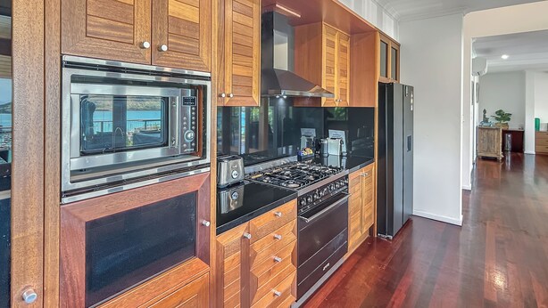 Una cocina moderna con armarios de madera, electrodomésticos de acero inoxidable y encimera negra.
