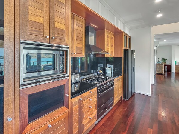 A modern kitchen with wooden cabinets, stainless steel appliances, and a black countertop.