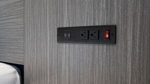 A wall-mounted electrical outlet with two USB ports and a power socket, set against a textured wall. - La Mirage Inn - Long Beach (Long Beach)