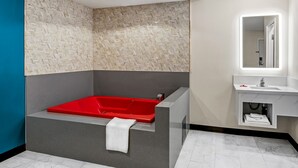A modern bathroom with a red jacuzzi tub, a white sink, and a mirror above the sink. - La Mirage Inn - Long Beach (Long Beach)