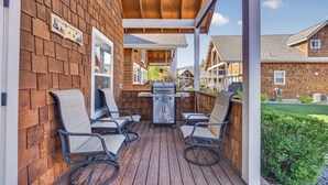A covered patio with a grill, four chairs, and a sign reading 'On Golden Pond Orchard.' - Dog Friendly Bungalow in the heart of Dover Bay (Dover)