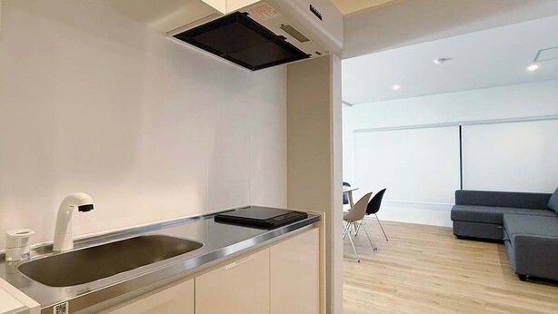 A modern kitchen with a built-in sink, a black range hood, and a grey countertop. - Vibrant 1BR, Downtown, Shopping & Dining Nearby 11 (Hiroshima)