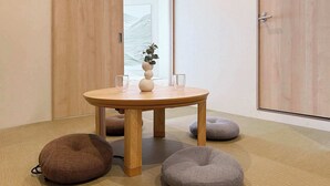 A room with a wooden table, two bean bags, and a vase with a plant. - 2BR, 2 Baths | Vibrant Downtown Near Shopping 21 (Hiroshima)