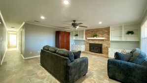 A spacious living room with a fireplace, two sofas, and a ceiling fan. - Charming, newly remodeled 2-bedroom duplex near Carthage w/ AC, fast WiFi (Carthage)