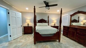 A four-poster bed with a ceiling fan, two bedside tables with lamps, a large mirror, and a wooden dresser. - Charming, newly remodeled 2-bedroom duplex near Carthage w/ AC, fast WiFi (Carthage)