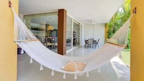 A hammock in a spacious, well-lit room with a glass door leading to a dining area. - El Tigre: Luxury, Pool, Golf view and near Beaches! (Nuevo Vallarta)