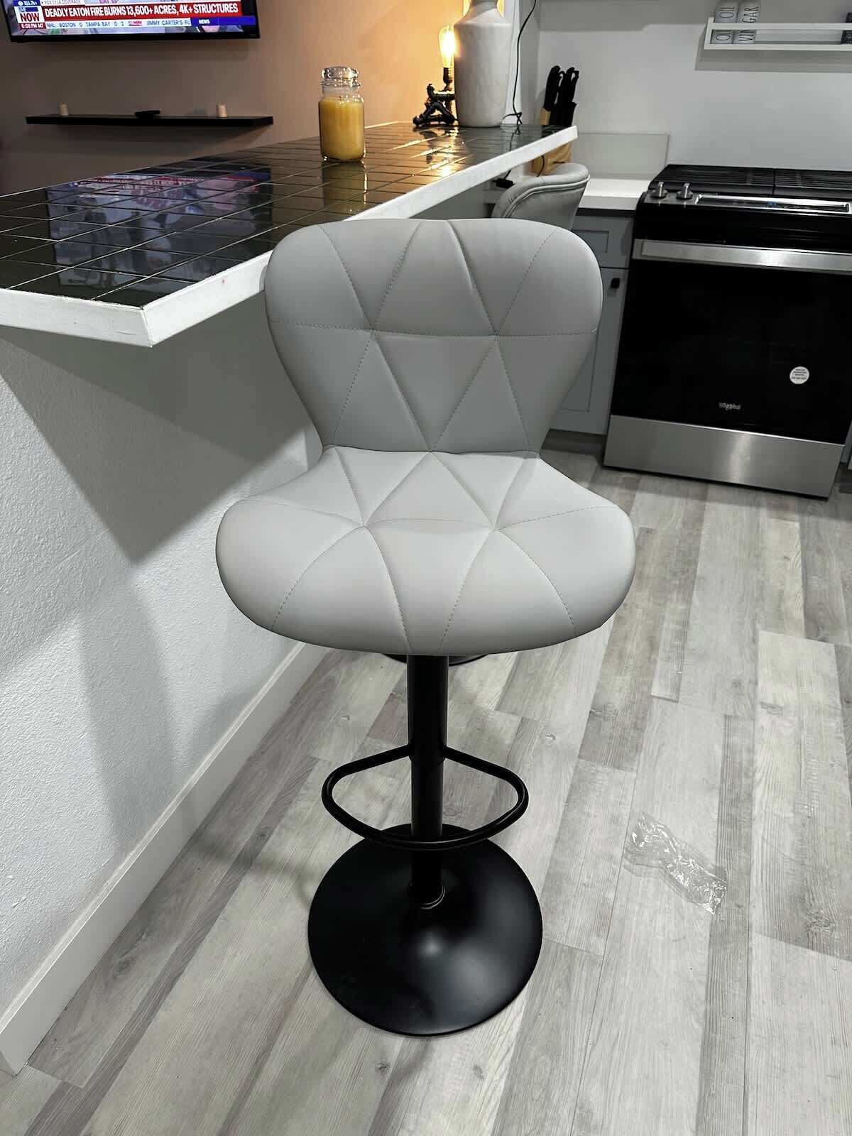 Une cuisine moderne avec un tabouret de bar blanc, un lave-vaisselle en acier inoxydable et un pare-feu en carreaux.