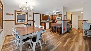 Una cocina amplia con armarios de madera, una mesa de comedor con sillas y una araña.