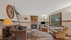 Una sala de estar con chimenea, un sofá, un sillón reclinable y una mesa de centro.