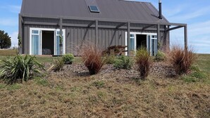 A modern house with a grey exterior, large windows, and a chimney. - Beautiful Wairarapa views, short drive to all Martinborough has to offer (Martinborough)