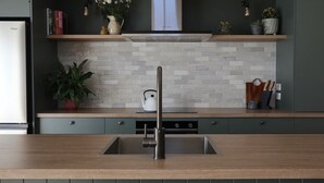 A modern kitchen with a stainless steel sink, a built-in range hood, and a wooden countertop. - Beautiful Wairarapa views, short drive to all Martinborough has to offer (Martinborough)