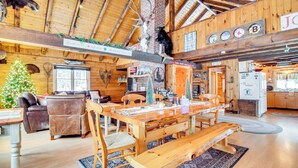 Interior acogedor de una cabaña con una mesa de comedor de madera, bancos y un árbol de Navidad.
