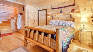 Un dormitorio de cabaña de madera con una cama, una mesita de noche, una lámpara y una decoración de estrella en la pared.