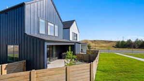 A modern two-story house with a large garage, a wooden fence, and a grassy yard. - Gateway to Yellowstone (Livingston)