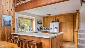 Una cocina con armarios de madera, encimera blanca y una isla integrada con taburetes.