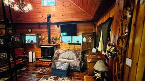 Een gezellig interieur van een blokhut met houten wanden, een open haard, een bank en een eettafel.