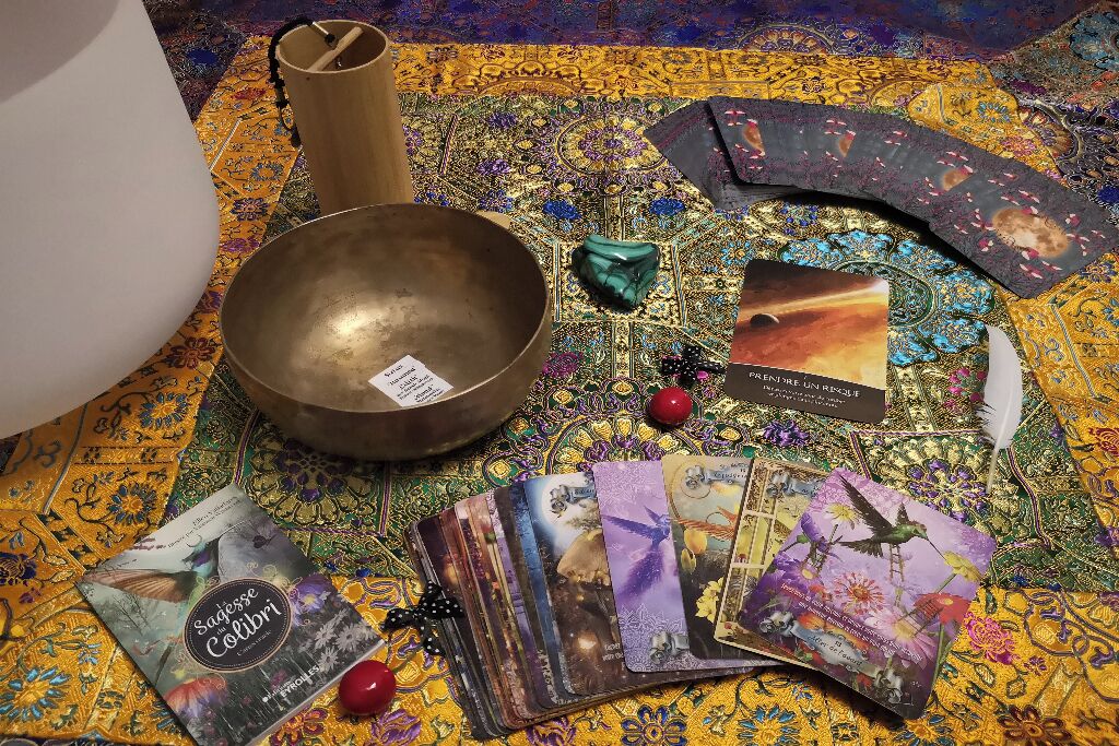 Tarot cards, a bowl, and a book on a patterned carpet.