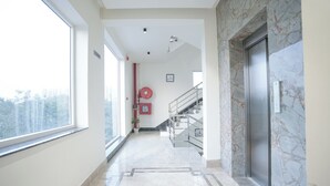 Un couloir moderne avec un sol en marbre, un escalier et un ascenseur.
