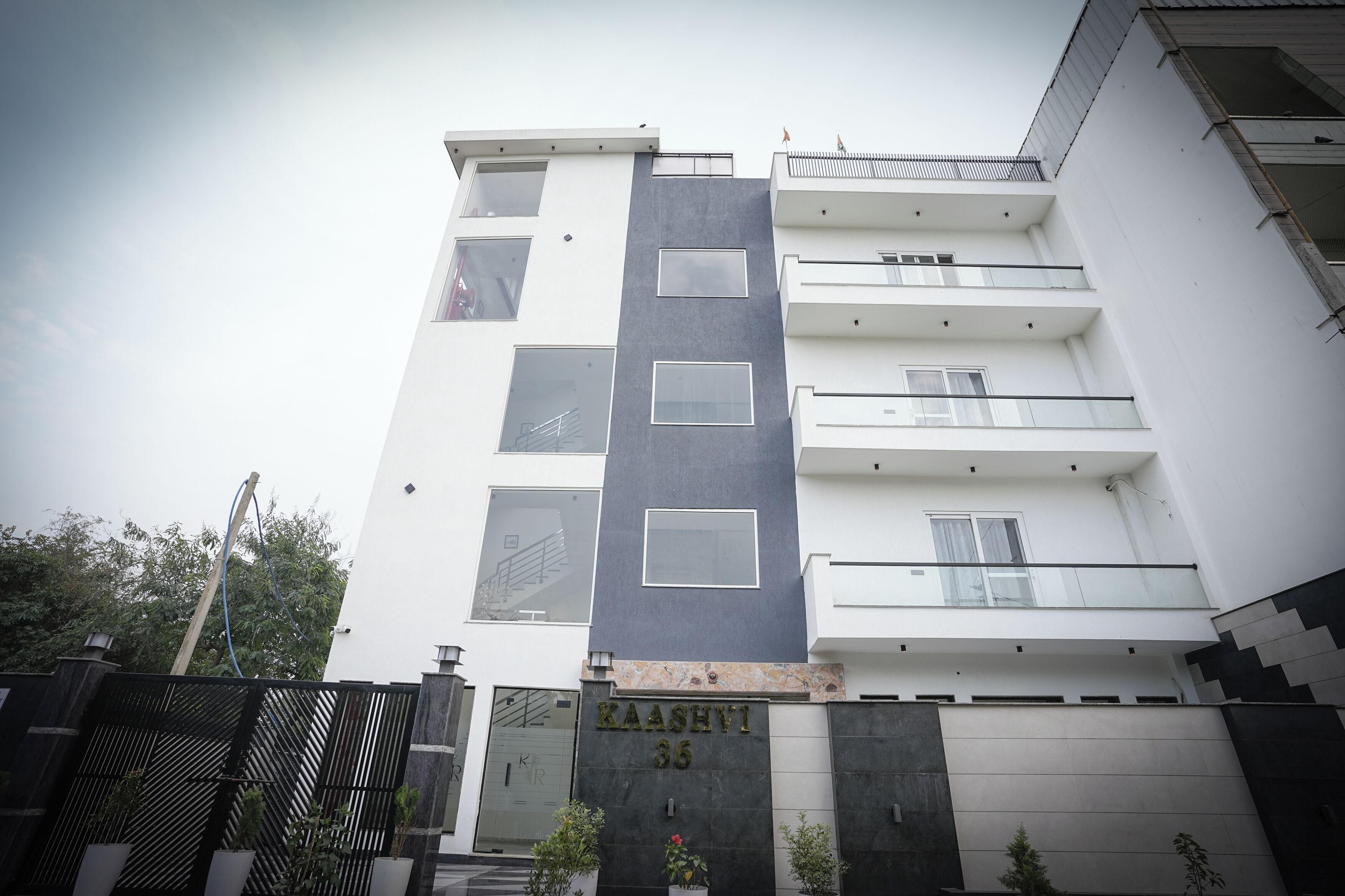 A multi-story building with a modern facade, featuring a prominent nameplate and a gated entrance.