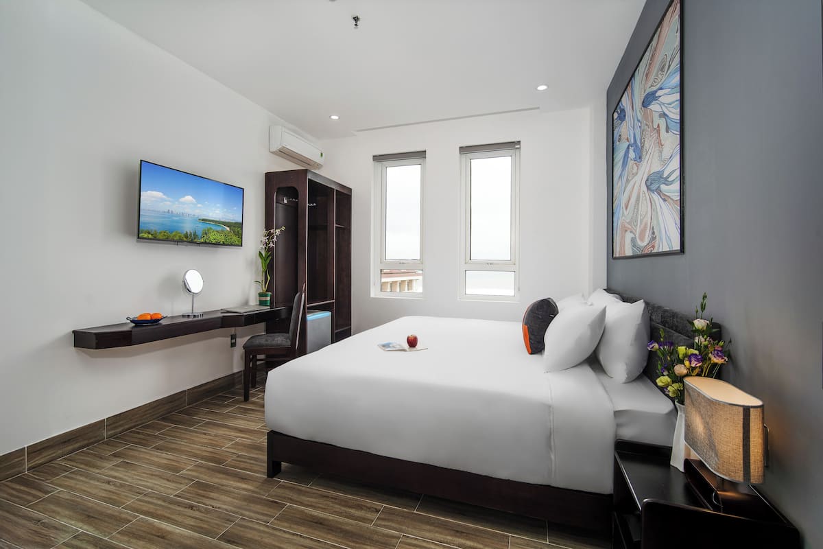 Een moderne hotelkamer met een groot bed, een flatscreen televisie, een bureau met stoel en een raam met uitzicht.