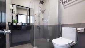 A modern bathroom with a glass-enclosed shower, a toilet, and a sink with a mirror above. - Coral Cove Hotel (Da Nang)