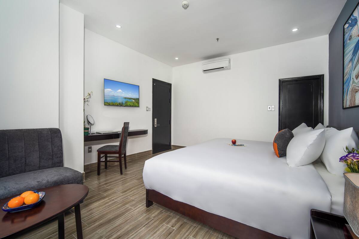Een hotelkamer met een groot bed, een bureau, een stoel en een klein tafeltje met fruit.