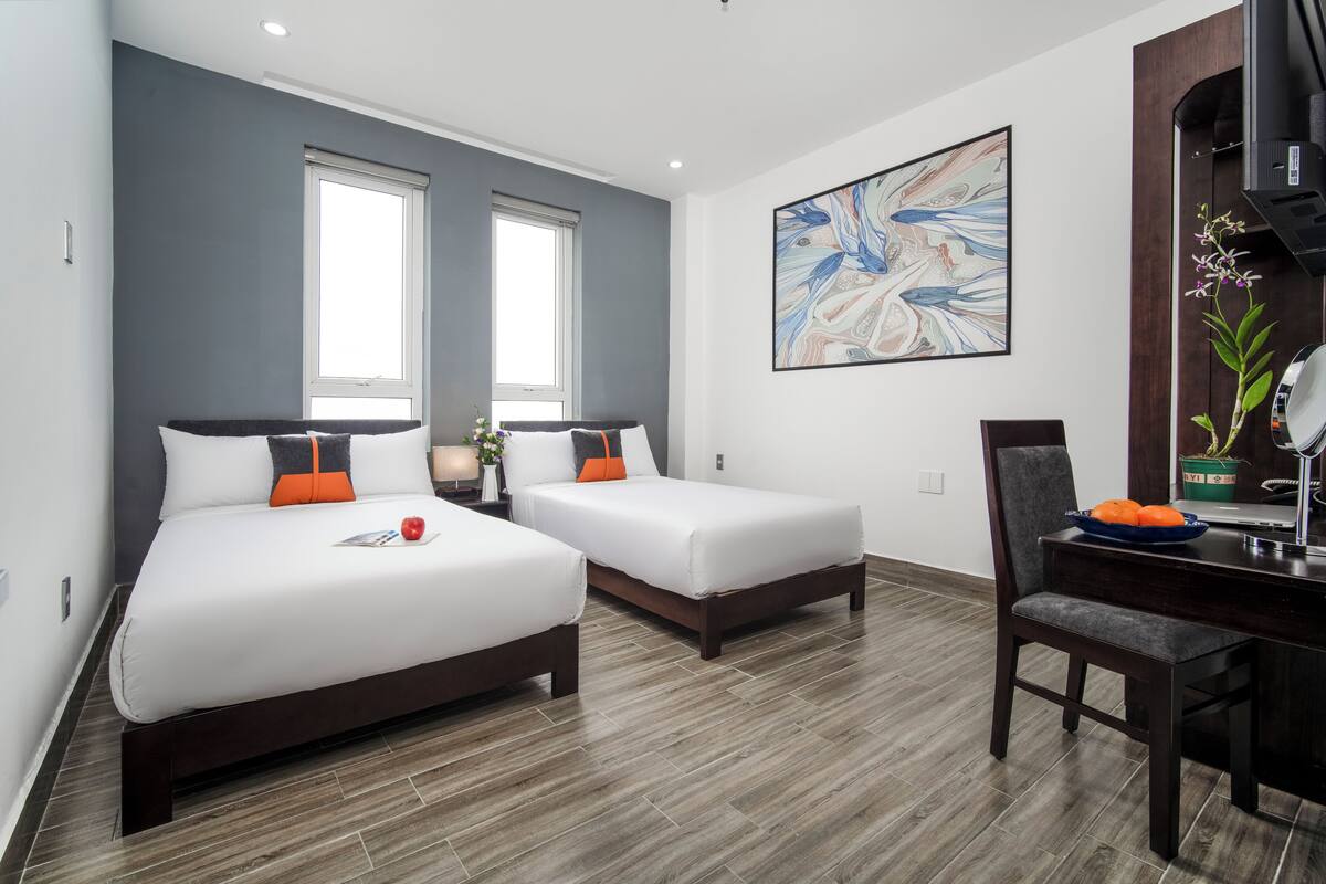 Een hotelkamer met twee bedden, een bureau en een groot abstract schilderij aan de muur.