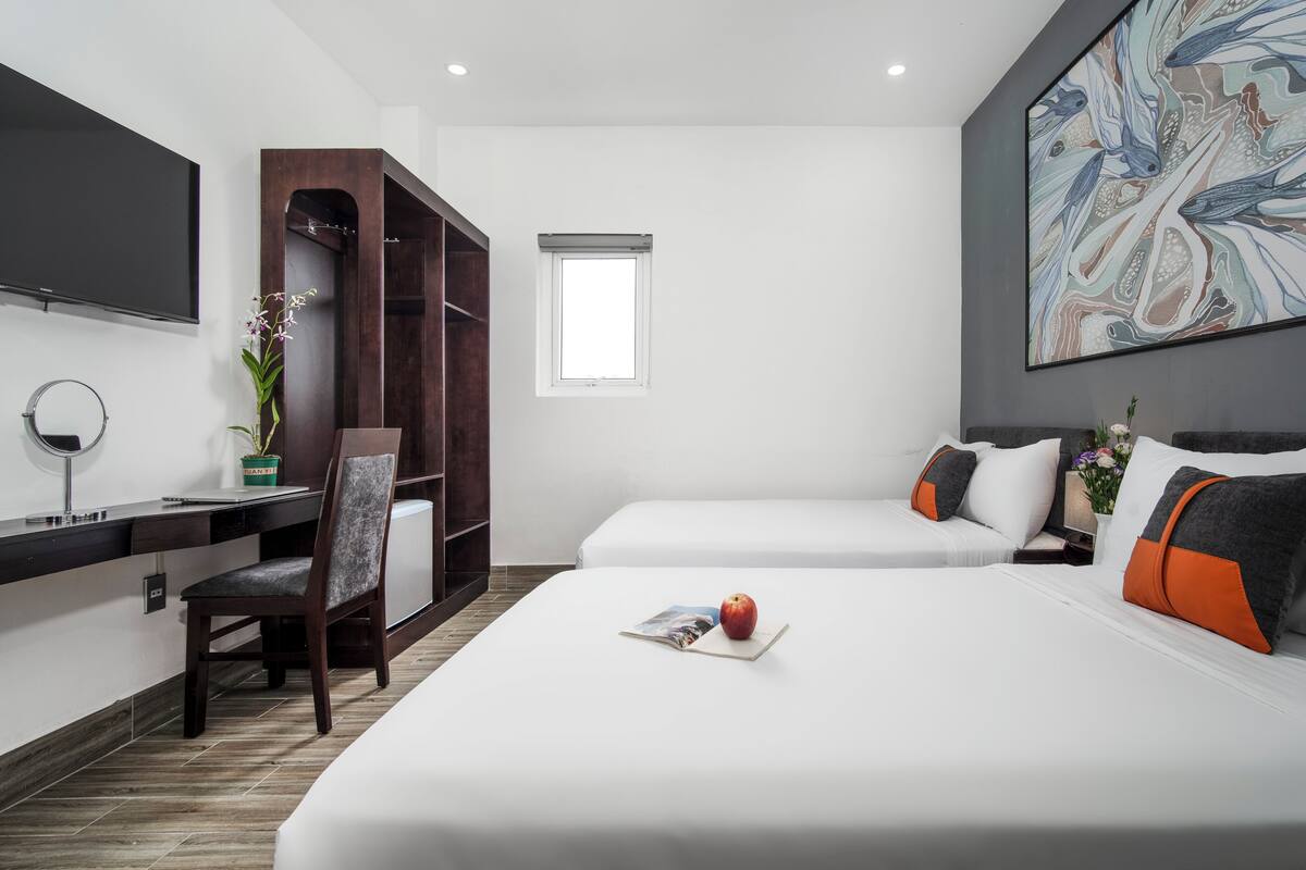 Een hotelkamer met een bed, bureau, stoel, televisie en raam.