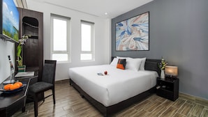 A modern hotel room with a large bed, a desk with a laptop, a chair, and a TV. - Coral Cove Hotel (Da Nang)
