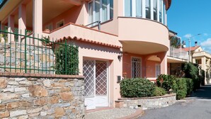 Una casa de dos pisos con fachada de piedra, un balcón y un pequeño jardín.