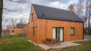 A wooden cabin with a sloped roof, a wooden deck, and a picnic table. - Villa in Cervene Janovice Near Kutna Hora Castle (Červené Janovice)